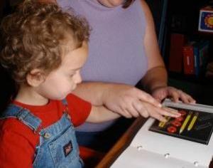 Young child touches tactile book with adult guidance.
