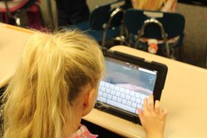 a girl looking at an ipad screen with a keyboard on it