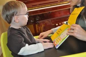 Young boy with glasses looks at a picture book