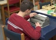 A boy uses a braillewriter.