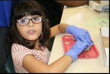 Girl wearing gloves doing a project at a table