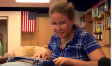 Girl with glasses using braillewriter