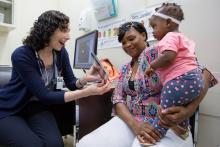 Pediatrician showing picture book to mother and baby