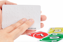 Fingers reading braille on UNO card