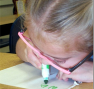 A second grade girl using a colored marker