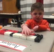 A boy touches the braille blocks on his desk.