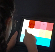 A girl uses an iPad with colored patterns on it.