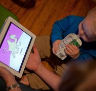 Toddler looking at tablet with picture of camel on it.
