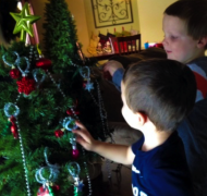 Two boys hanging ornaments on Christmas tree
