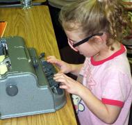 A young girl uses a braillewriter