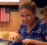 Girl with glasses using braillewriter