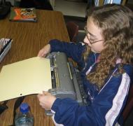 A girl putting braille paper into her Perkins braillewriter