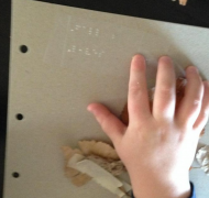 A child's hand reads braille about fall leaves