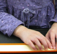 Child's hands reading a line of braille