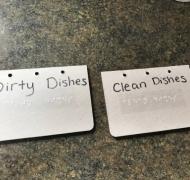 two magnets labeled in print and braille, one says dirty dishes and the other says clean dishes 