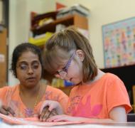 Girl with her hand resting on teacher's hand