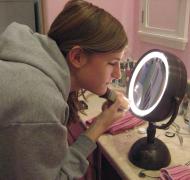 A teenage girl puts on makeup