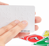 Fingers reading braille on UNO card