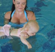 woman holds baby in pool