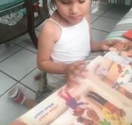 A young girl examines a tactile book with text in English and Spanish.