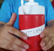 Hands holding a thermos with braille on it