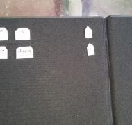 The braille words I, cheese, pizza, and like and a period are on small plastic tiles on a black felt board from APH.