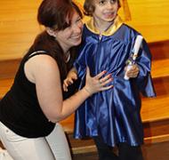 A woman kneels next to a child in a cap and gown