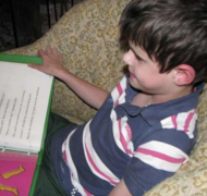 A boy with a braille book from APH on his lap.
