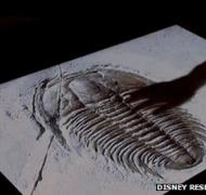 A hand touches a touchscreen of a trilobite