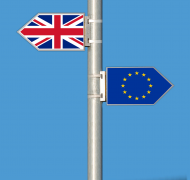 a sign post with one sign showing the British flag and one flag showing the EU flag