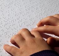 image of girl's hands reading a braille page