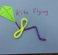 Front page of "Kite Flying" book; shows a kite made out of foam and the kite strings made out of pipe cleaners