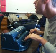 Photo: Student at table working on his braillewriter