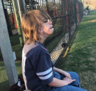 Boy sitting on bench at athletic field