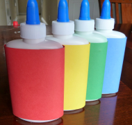 Four squeeze bottles of puff paint colored red, yellow, green, and blue.