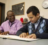 A teacher and student read braille together