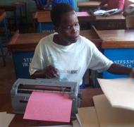 A secondary student in Africa uses a braillewriter.