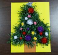 garland shaped into a tree with fuzzy pom poms on a piece of yellow paper