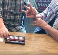 A boy who is deafblind uses an abacus with his interpreter