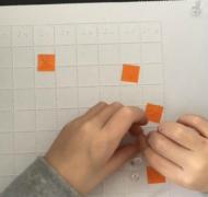Two hands with push pins on Battleship grid