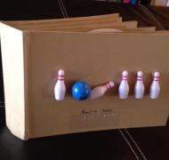 a cardboard book with toy bowling pins and a bowling ball on the cover