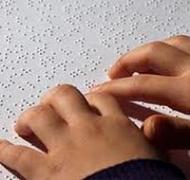 Image of child's hands reading braille text
