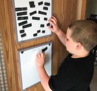 A boy reads a braille grocery list on magnetic strips