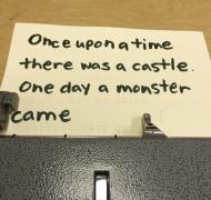 paper in Perkins brailler, scribbled braille interlined with large print words which reads, once upon a time there was a castle. One day a monster came