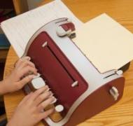 Student writing on a braille writer
