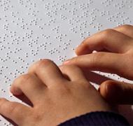 child's hands reading braille