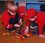 Young children place with math manipulatives on the floor.