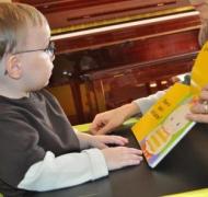 Young boy with glasses looks at a picture book