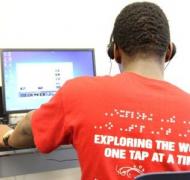 A teenage boy sits at a computer.