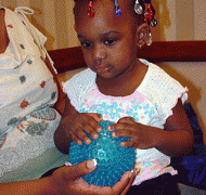 A young girl examines a textured ball.